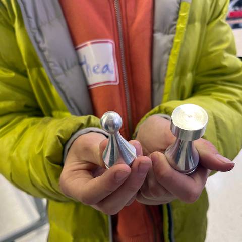 A local middle school student holds chess pieces made by CNC Machine Technology students