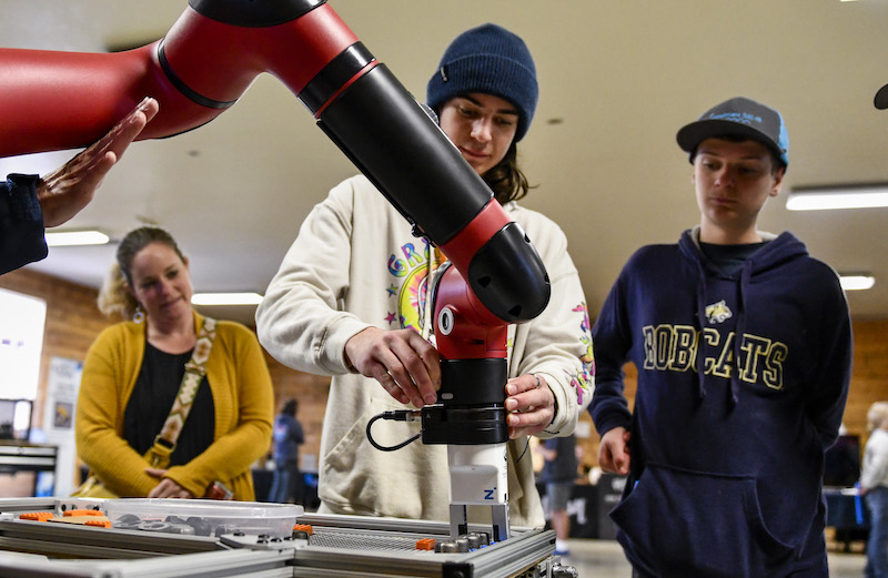 two middle school students testing a robotic arm