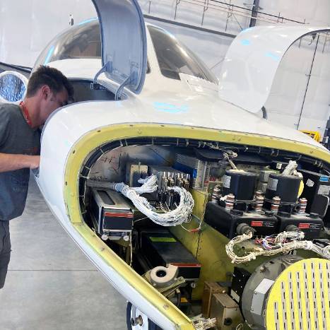 Aviationics technician working on a plane's electrical system.